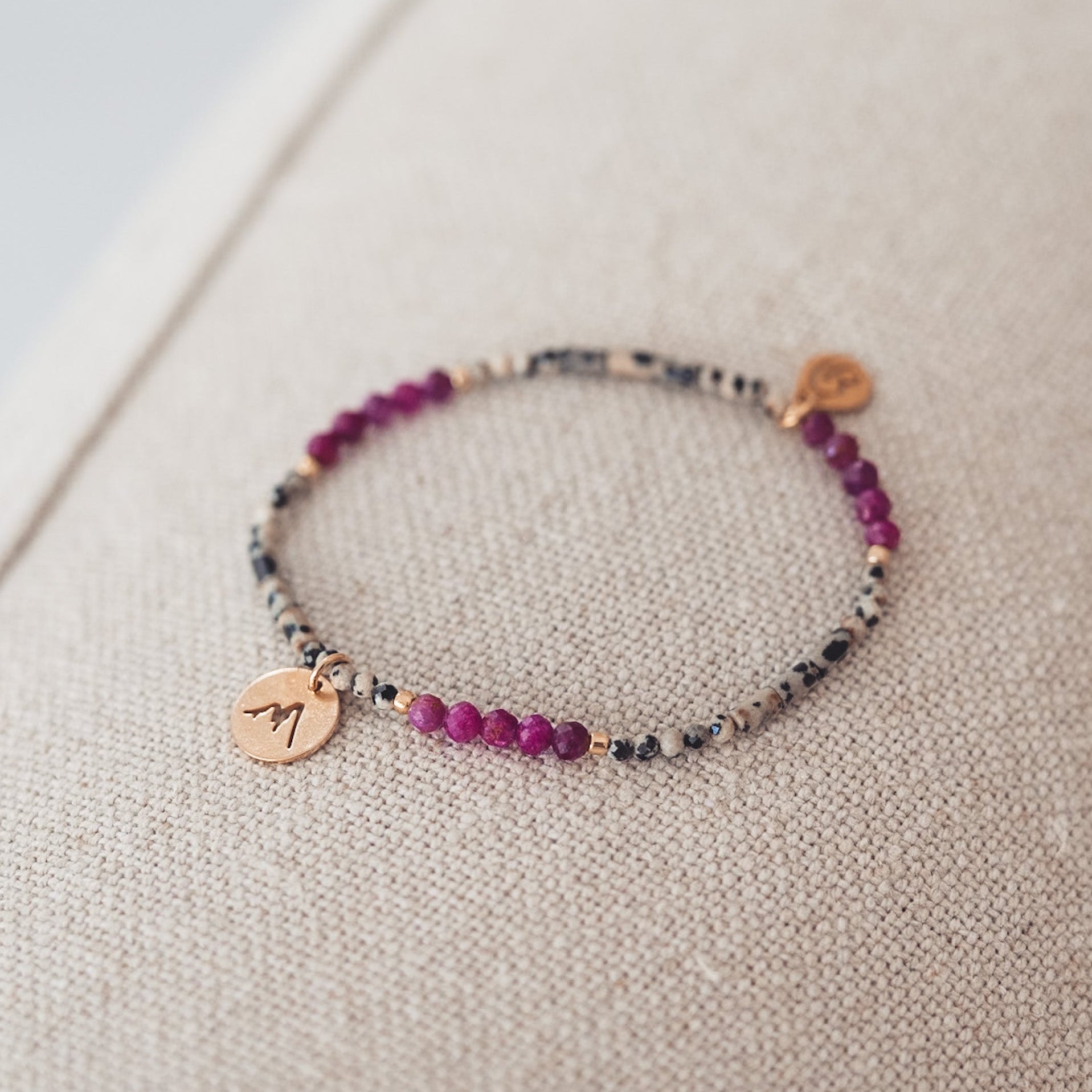 Bransoletka z dalmatyńskich i fuksjowych koralików z pozłacaną zawieszką.